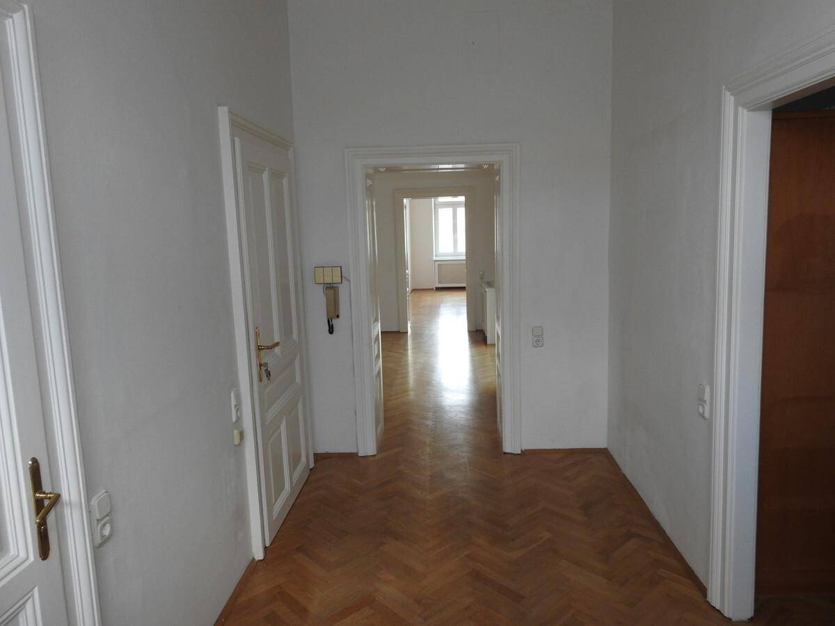 Heller Flur mit klassischem Fischgrätparkettboden, der zu weiteren Zimmern der Wohnung führt.