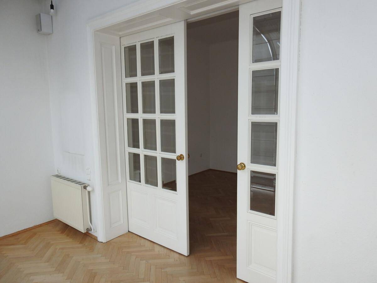 Elegante Doppeltüren mit Glaseinsätzen, die einen Übergang zu einem weiteren Raum schaffen.