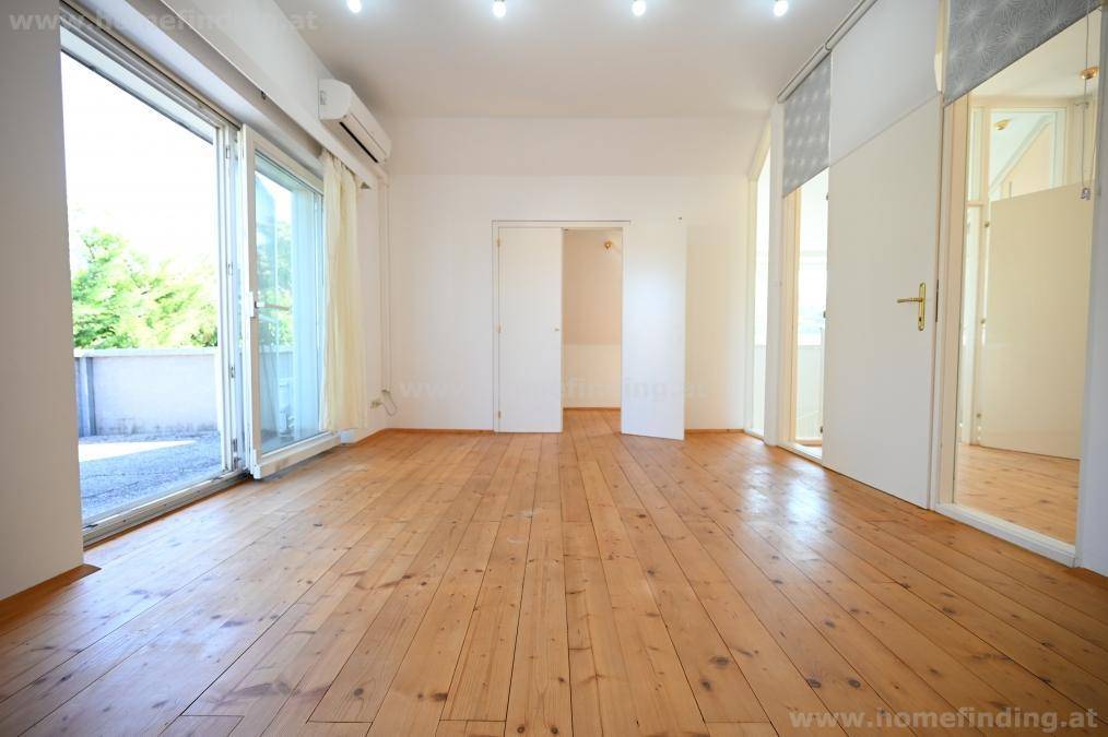 Helles Schlafzimmer mit Holzplankenboden, Zugang zu einem Balkon und Klimaanlage.