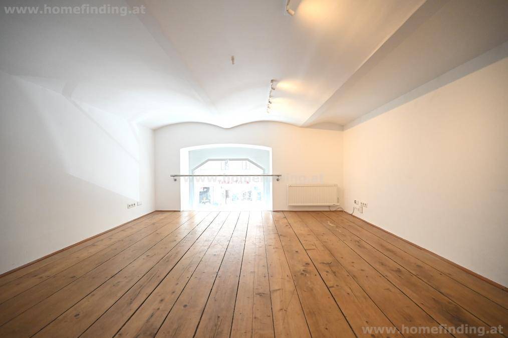 Heller Raum mit Dielenboden, gewölbter Decke und einem großen Bogenfenster mit Geländer.