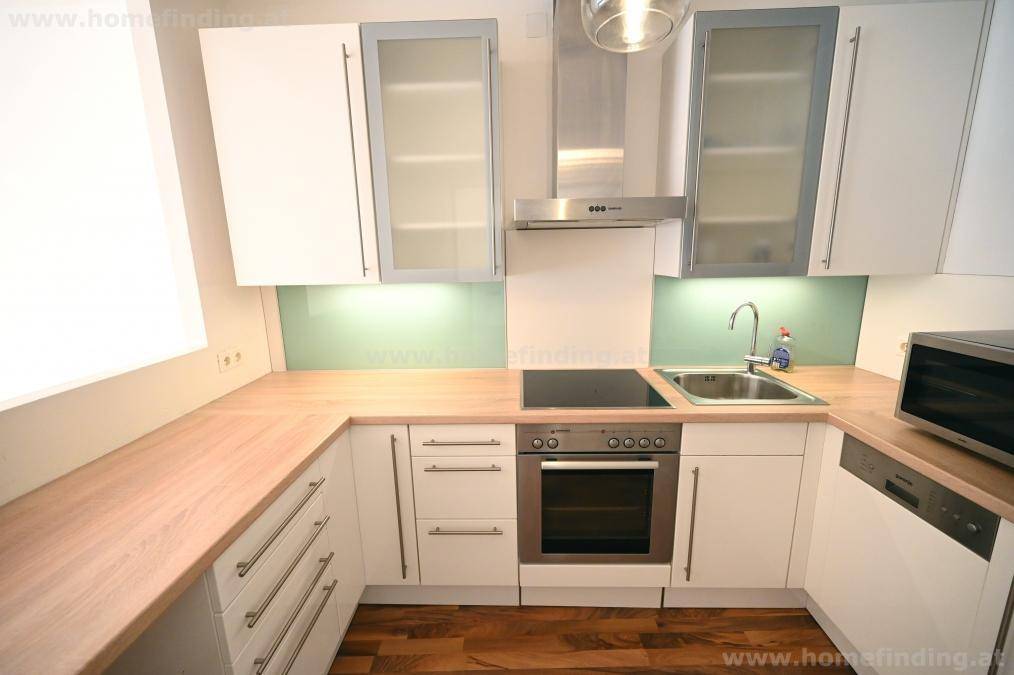Detailansicht der modernen Küche mit Induktionskochfeld, Backofen, Spülmaschine und viel Arbeitsfläche.