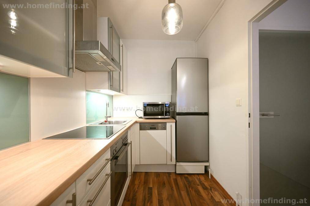 Funktionale Küche mit integriertem Kühlschrank, Mikrowelle und Holzarbeitsflächen, ideal für den Alltag.