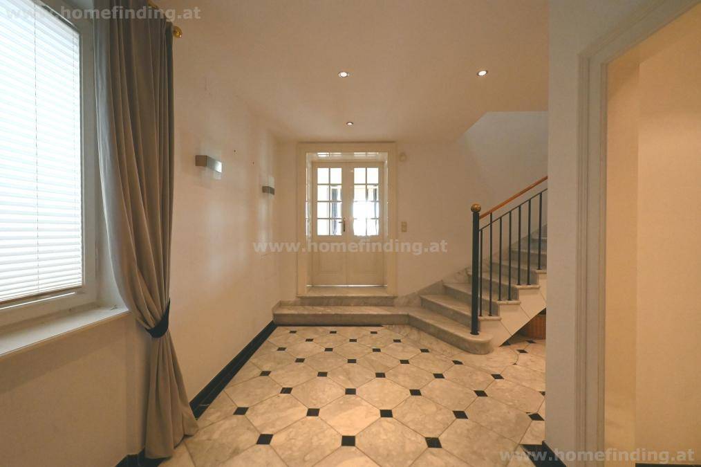 Eingangsbereich mit Marmorfliesen, Treppe zum Obergeschoss und natürlichem Lichteinfall.