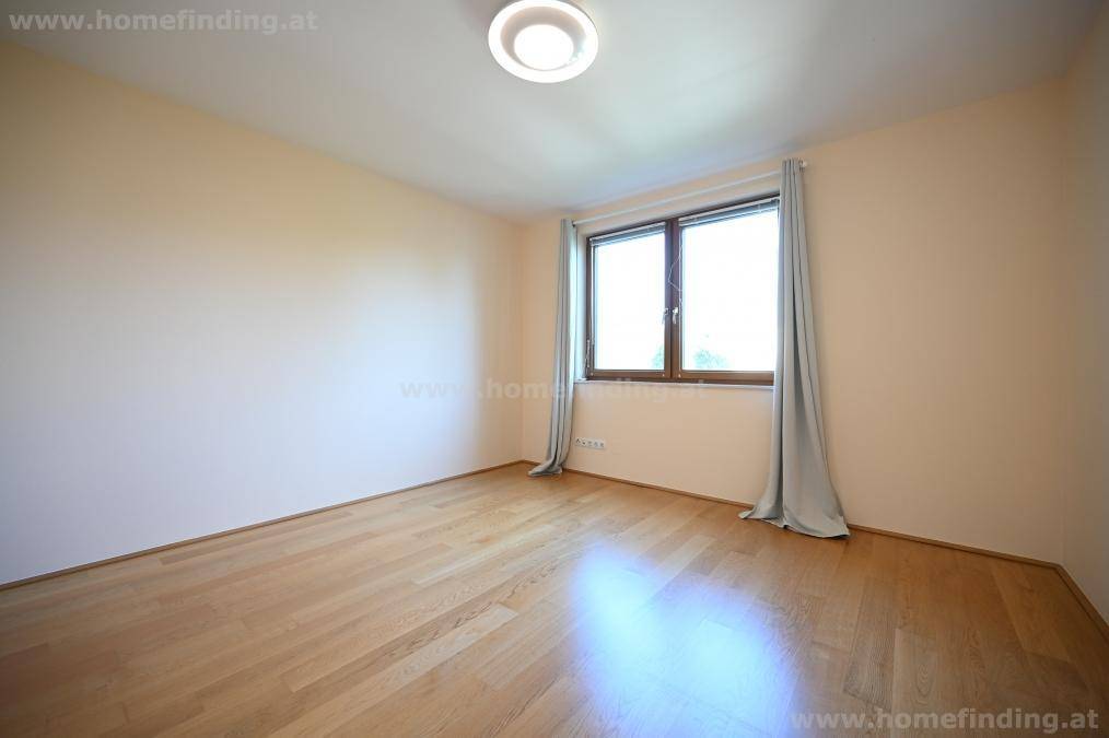Geräumiges Schlafzimmer mit hellem Parkettboden und einem Fenster, das den Raum mit natürlichem Licht erfüllt.