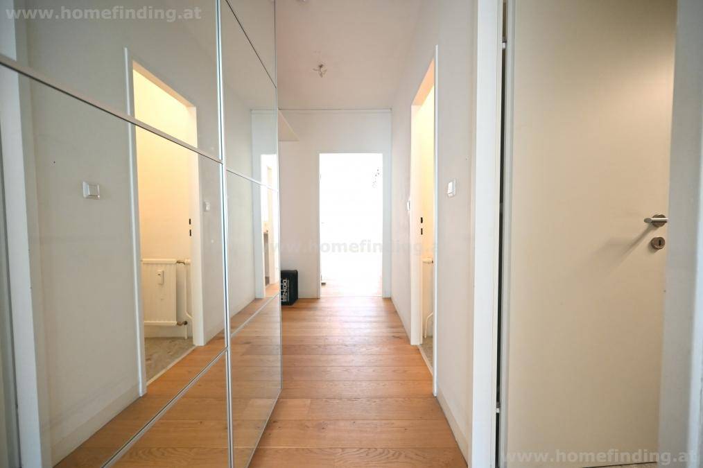Langer Flur mit Spiegelschränken und hellem Holzfußboden, der zu weiteren Räumen führt.