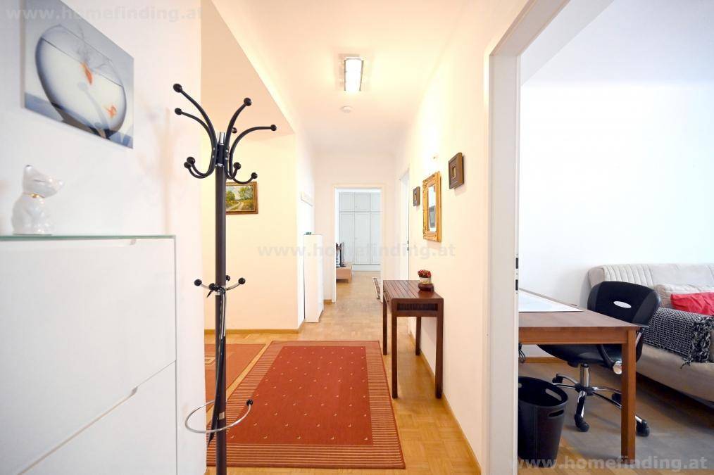 Langer Flur mit Garderobe, Schuhschrank und Parkettboden, der verschiedene Räume verbindet.