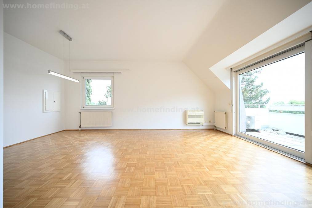 Heller Wohnraum mit Parkettboden, Heizkörpern und Zugang zu einem Außenbereich.