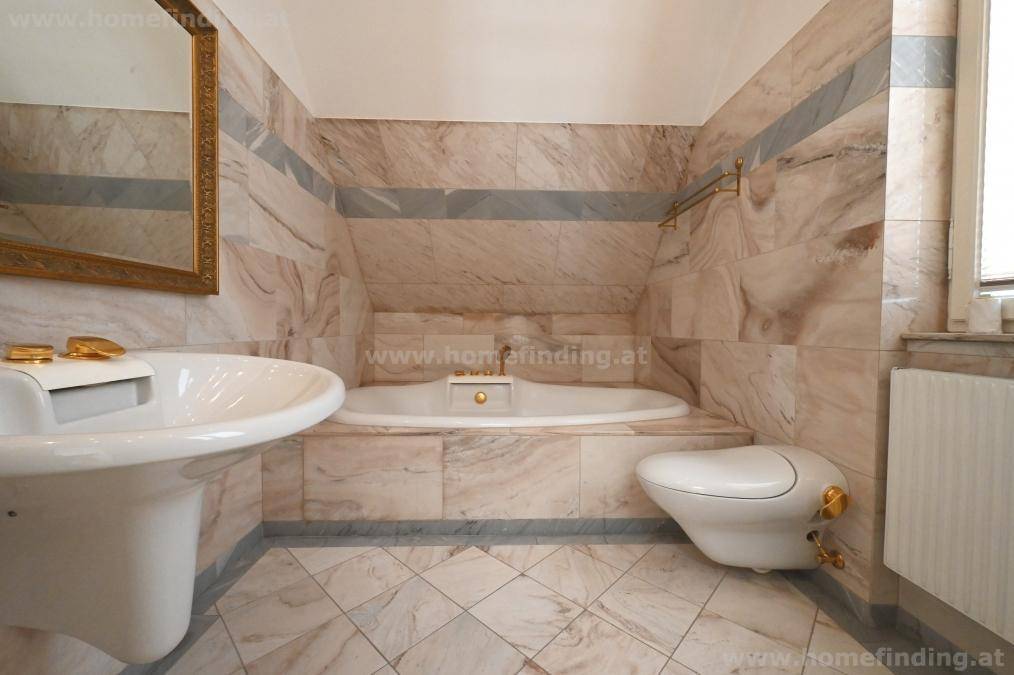 Elegantes Badezimmer mit Badewanne, Marmorfliesen und Dachschräge.