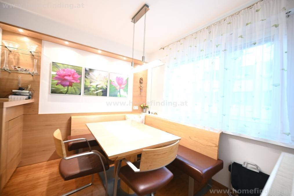 Gemütlicher Essbereich mit Holzbänken, Esstisch und Fenster mit hellen Vorhängen.