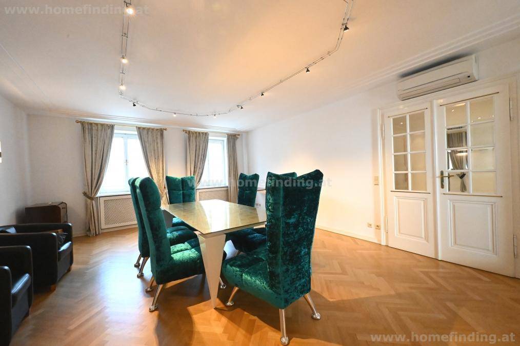 Elegantes Esszimmer mit Parkettboden, grünen Samtstühlen und doppelten Flügeltüren.