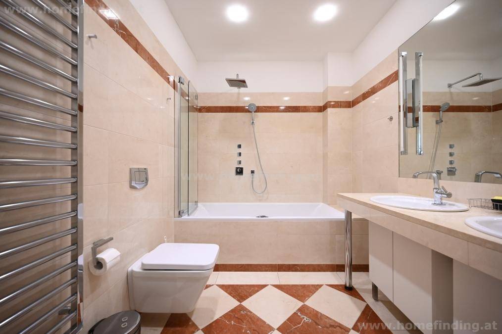 Geräumiges Badezimmer mit Badewanne, Dusche, Doppelwaschbecken und beheiztem Handtuchhalter für Komfort.