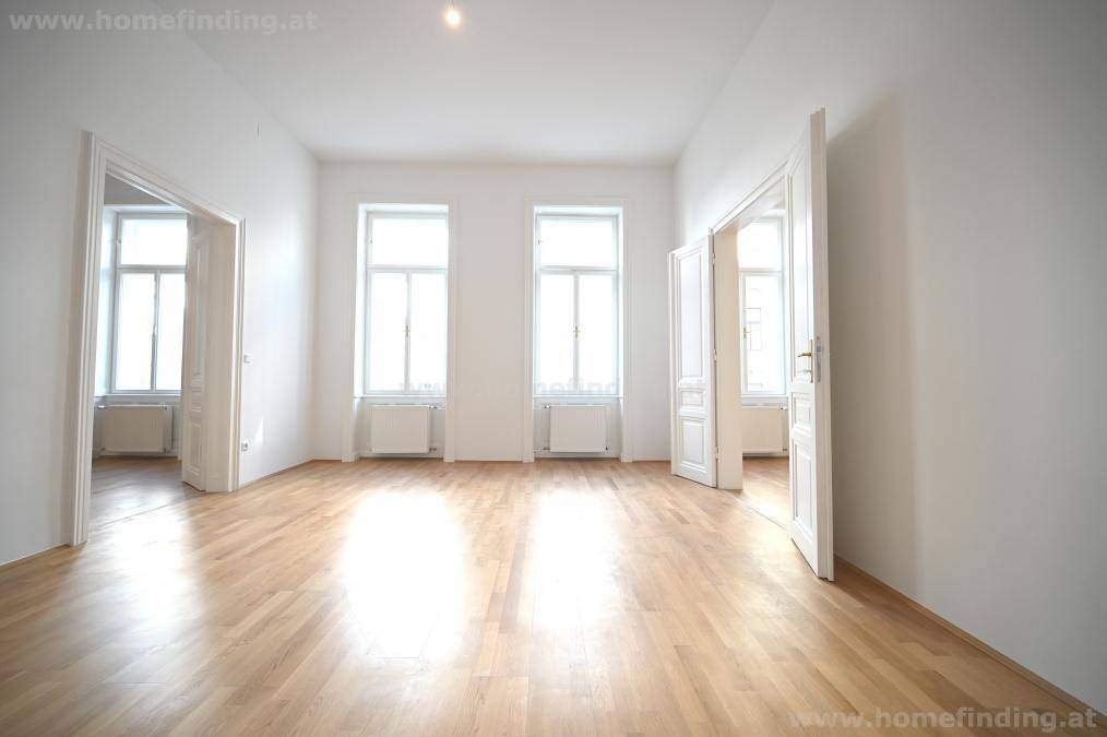Geräumiges Zimmer mit Parkettboden, drei Fenstern und mehreren Türen, sehr hell.