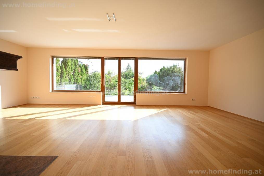 Geräumiges Wohnzimmer mit großen Fenstern, die einen schönen Blick ins Grüne bieten und viel Licht spenden.