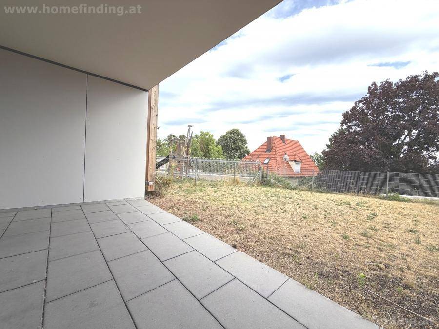 Gepflasterte Terrasse mit Blick auf einen Gartenbereich und das umliegende Grün.