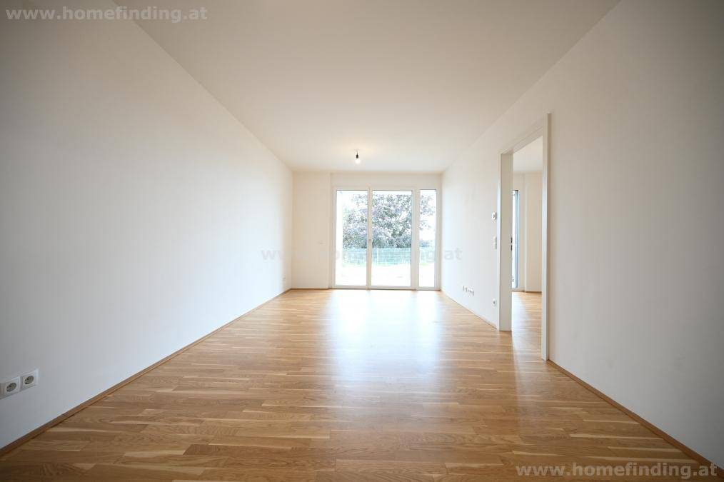 Geräumiges, helles Zimmer mit Holzboden und großen Fenstern, die viel Tageslicht hereinlassen.