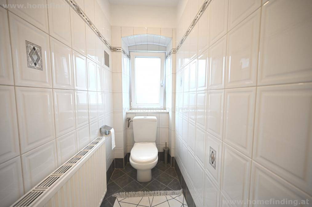 Separates WC mit Fenster, Toilette und weißen Fliesen, die für eine helle Atmosphäre sorgen.