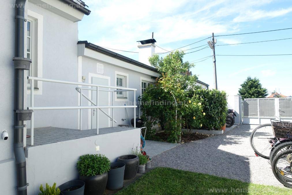 Hauszugang mit barrierefreier Rampe, Kiesweg und einer sichtbaren Überwachungskamera.