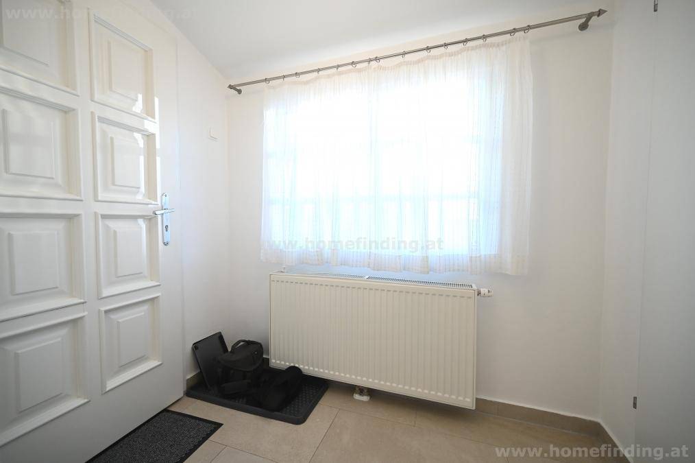 Heller Eingangsbereich mit Fliesenboden, Fenster und Heizkörper, einladend und funktional.