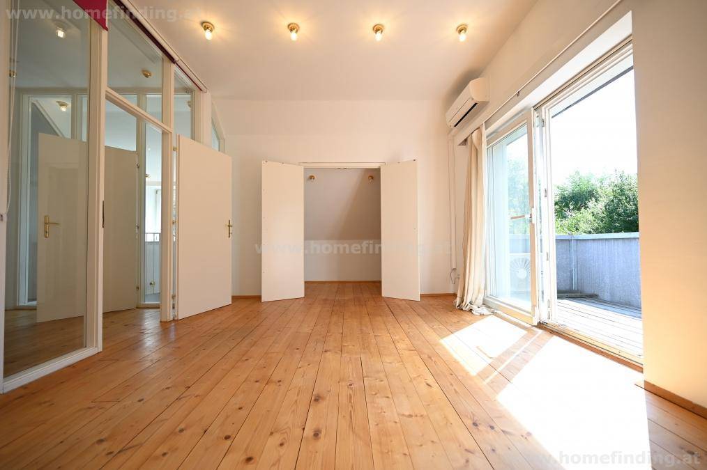 Schlafzimmer mit Holzplankenboden, viel Tageslicht und integriertem Stauraum.
