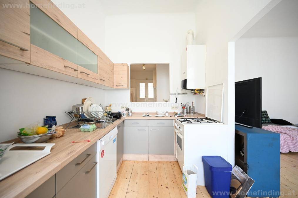 Funktionale Küche mit Holztheke, Gasherd und einem Durchgang zu einem angrenzenden Wohnbereich.