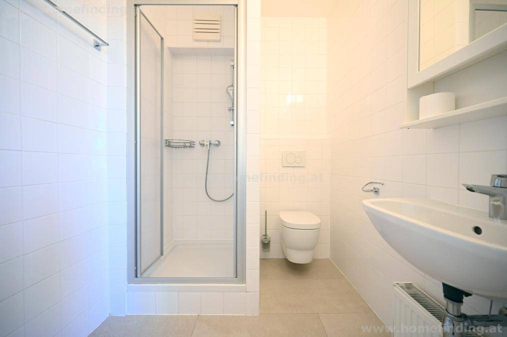 Modernes Badezimmer mit Duschkabine, wandhängendem WC und einem einzelnen Waschbecken.