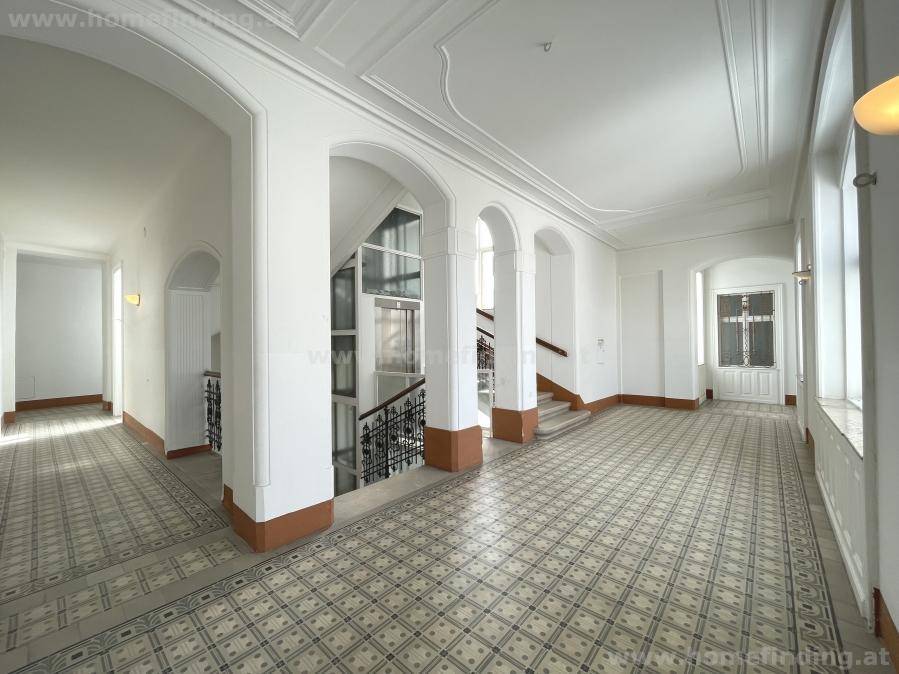 Repräsentativer Eingangsbereich mit hohen Decken, eleganten Bögen, Treppe und Aufzug.