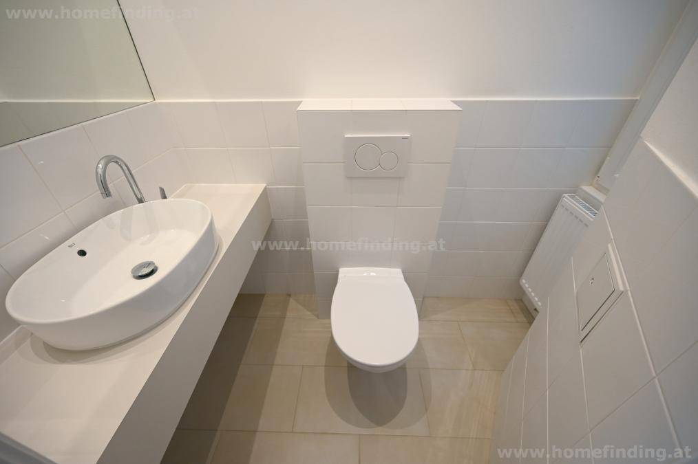 Modernes Gäste-WC mit wandhängendem WC und elegantem ovalem Waschbecken auf einer Ablage.