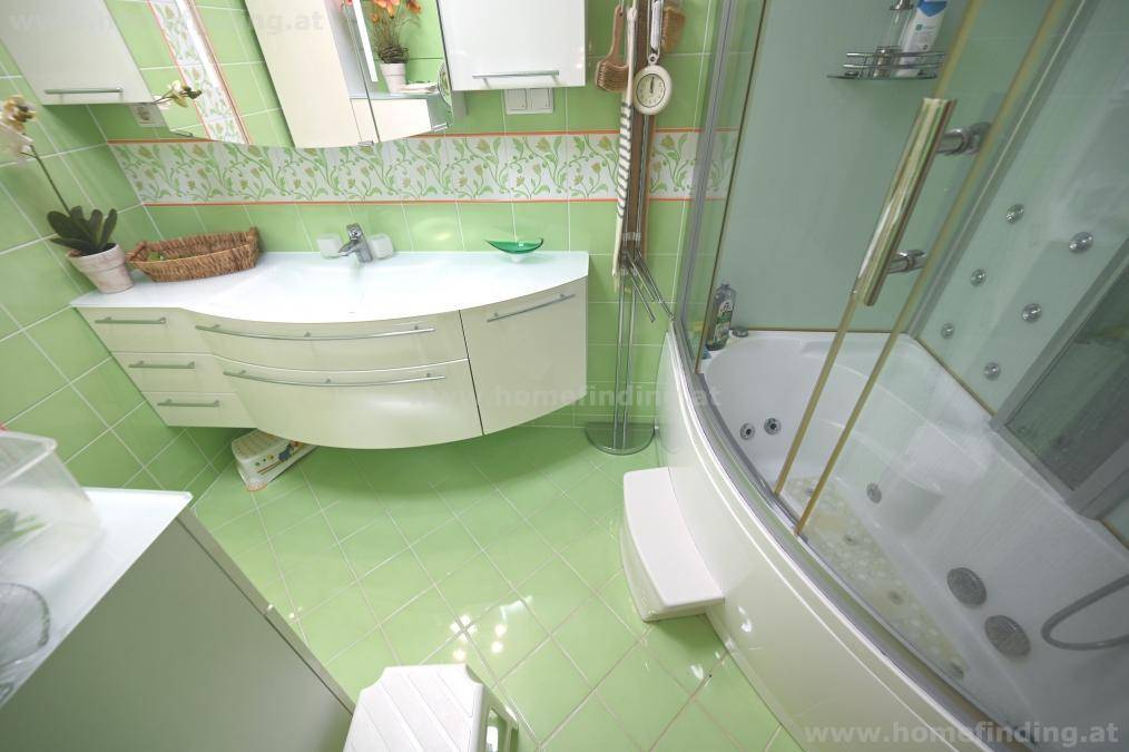Badezimmer mit hellgrünen Fliesen, modernem Waschtisch und Eck-Whirlpool-Dusche.