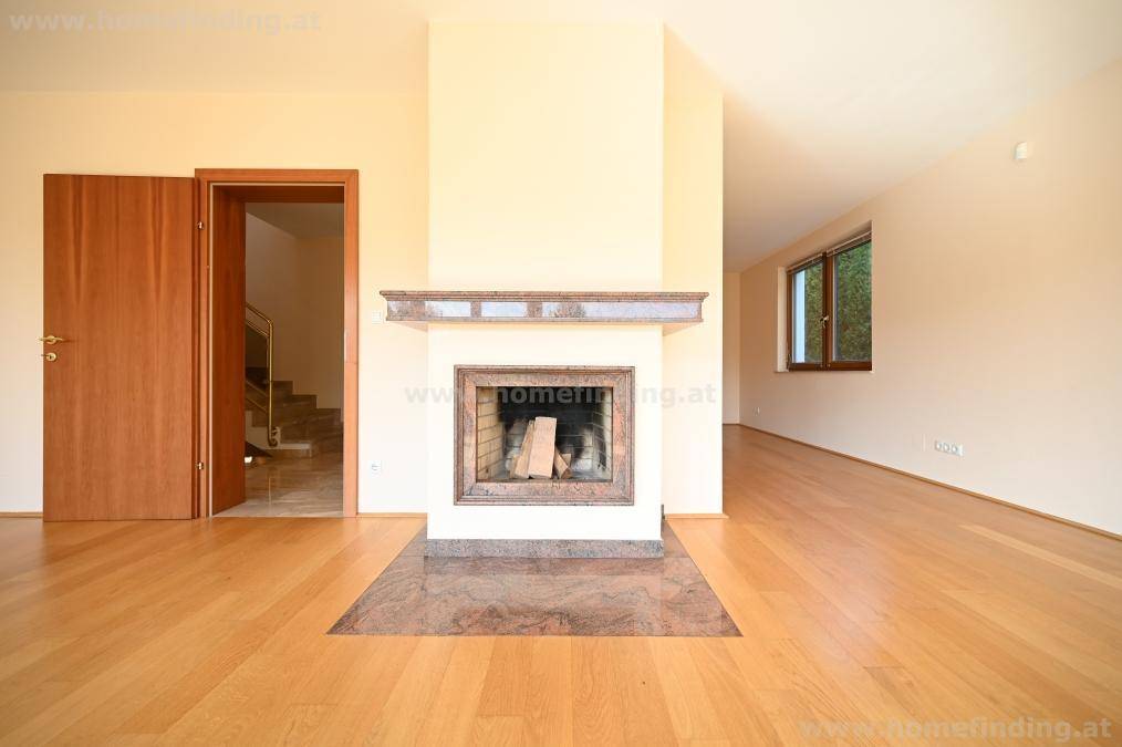 Gemütliches Wohnzimmer mit einem eleganten Kamin und Zugang zu einem Treppenhaus, ausgestattet mit Parkettboden.