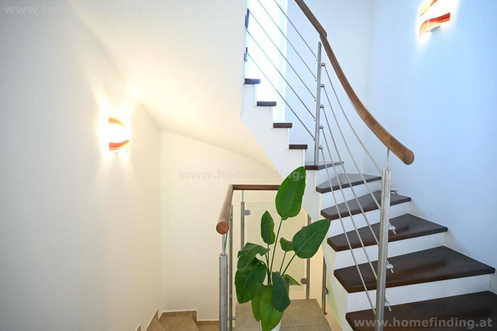 Elegante Treppe mit Holzstufen und modernem Edelstahlgeländer, die die Etagen verbindet.