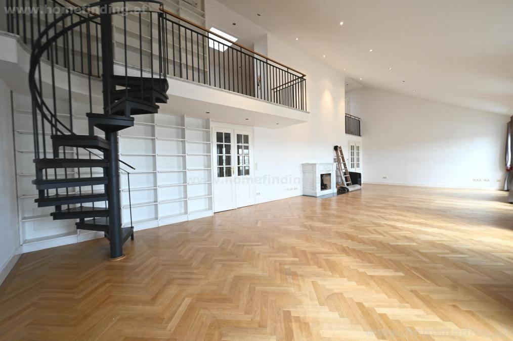 Helles Wohnzimmer mit hohen Decken, integrierten Bücherregalen und Wendeltreppe zur oberen Ebene.