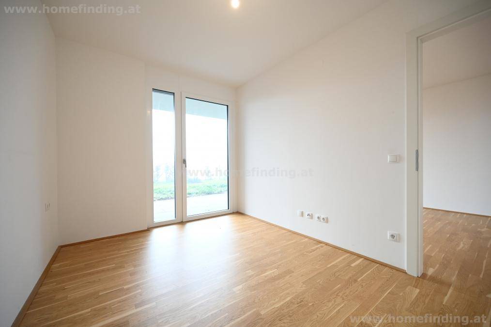 Helles Zimmer mit Parkettboden und großer Fenstertür, die den Raum mit natürlichem Licht erfüllt.
