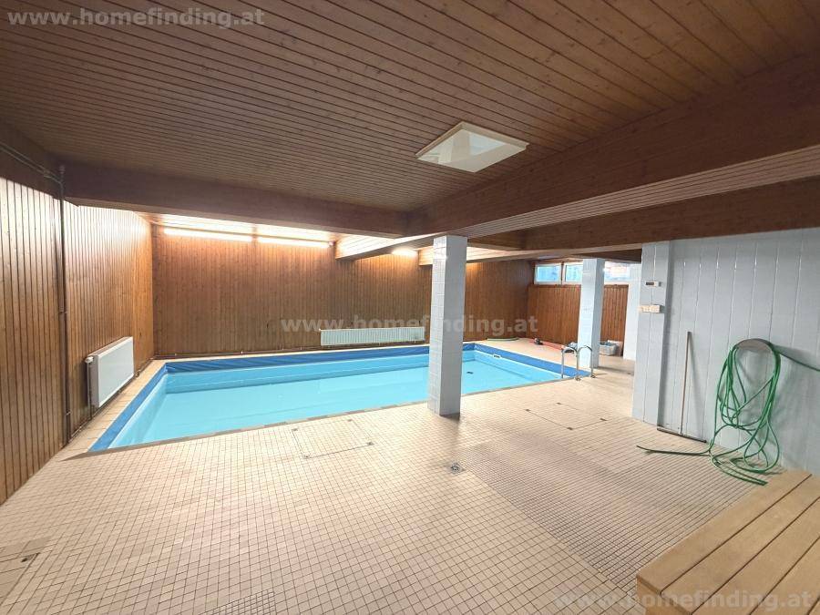 Innenpool mit Holzverkleidung an Wänden und Decke, umgeben von hellen Fliesen und Heizkörpern.