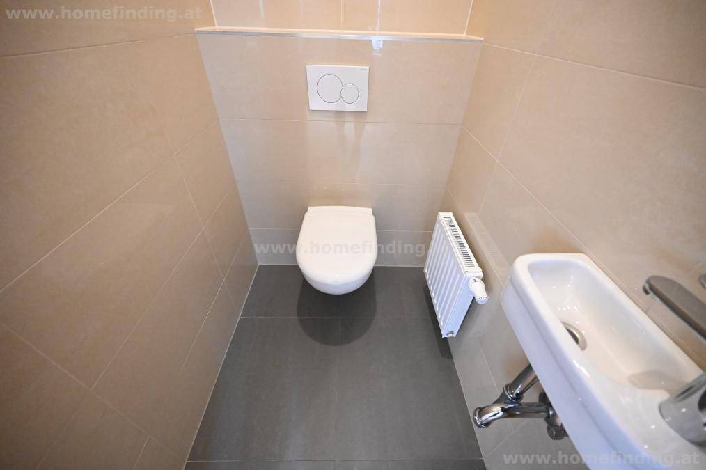 Separates WC mit wandhängender Toilette und kleinem Handwaschbecken.