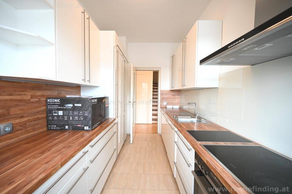 Gut ausgestattete Küche mit Induktionskochfeld, Holz-Arbeitsplatten und viel Stauraum.