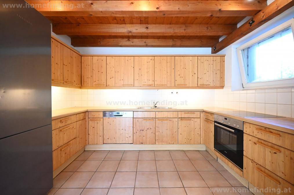 Funktionale Küche mit Holzschränken, integrierten Geräten und Fliesenboden.