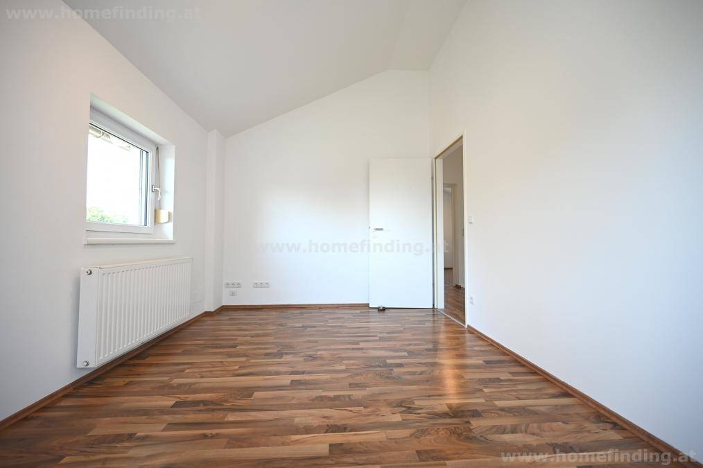 Geräumiges Schlafzimmer mit Parkettboden, Dachschräge und Zugang zu weiteren Räumen.