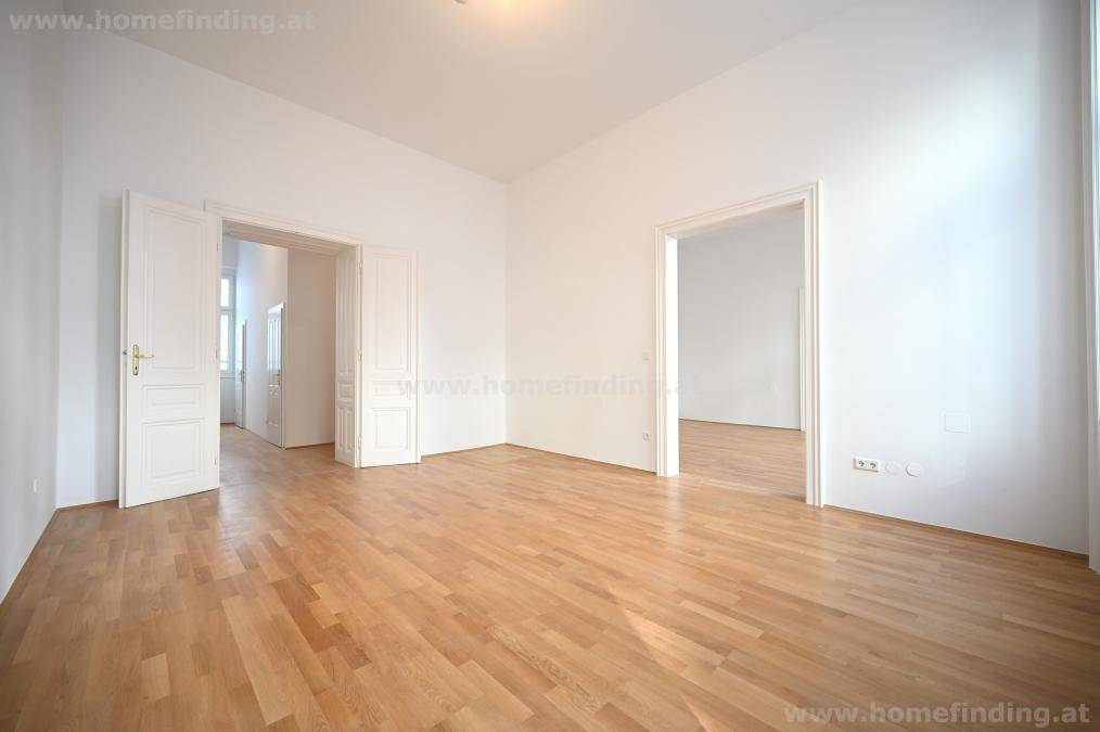 Geräumiges Zimmer mit hellem Parkettboden und mehreren Türen zu angrenzenden Räumen.