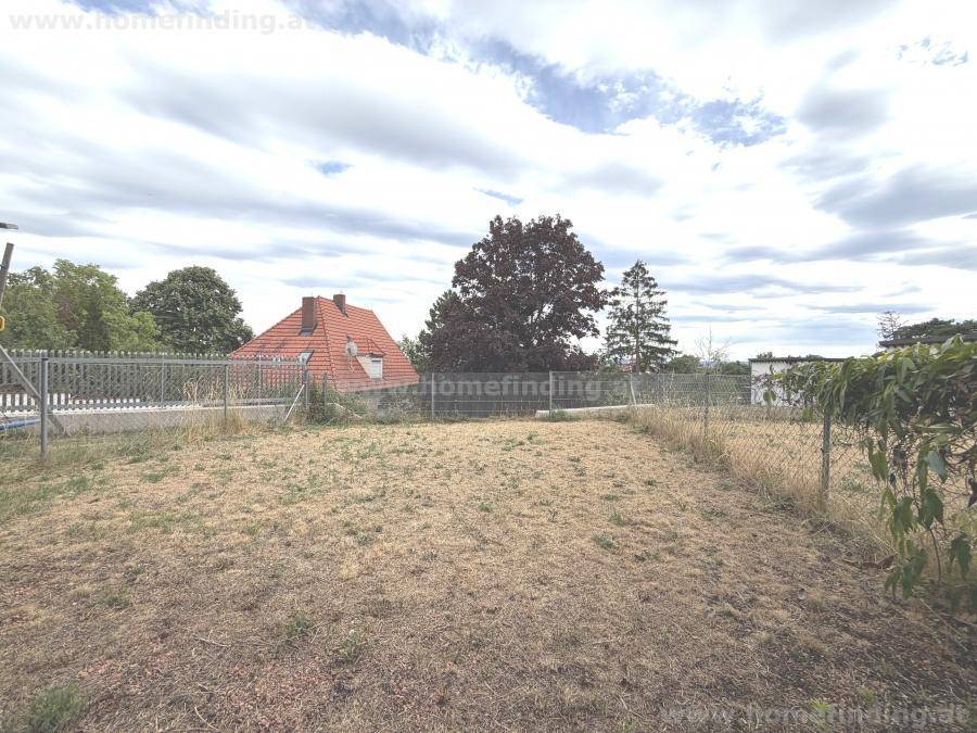 Großer Gartenbereich mit Rasenfläche und Blick auf die umliegende Landschaft und Häuser.