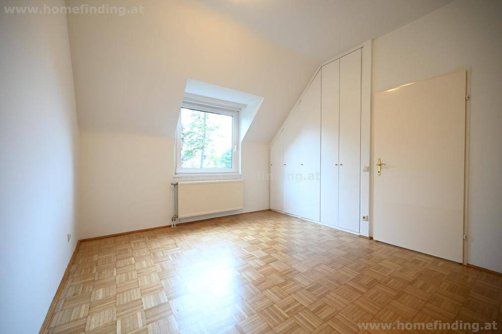 Helles Schlafzimmer mit Parkettboden, Fenster und integrierten Schränken.