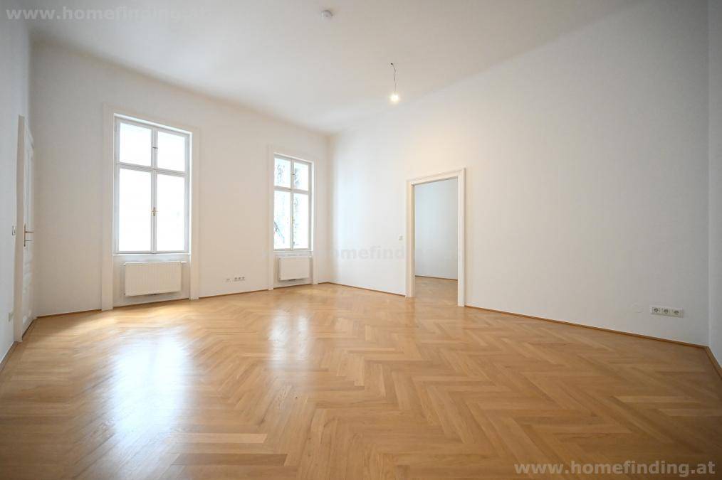 Geräumiges, helles Zimmer mit Fischgrätparkett und zwei großen Fenstern.