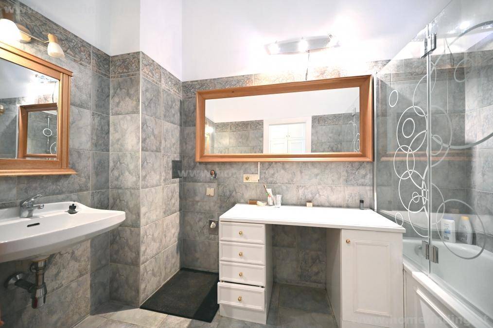 Gefliestes Badezimmer mit Waschbecken, großem Spiegel und einer Dusch-Badewannen-Kombination.