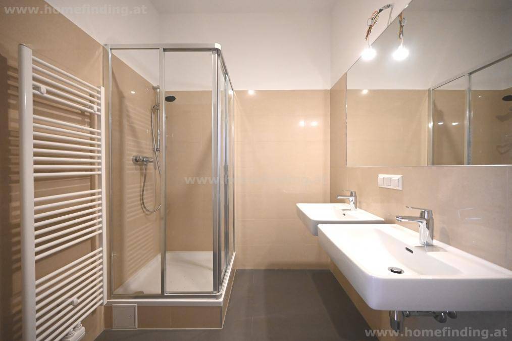 Modernes Badezimmer mit Doppelwaschbecken, Duschkabine und beheiztem Handtuchhalter.
