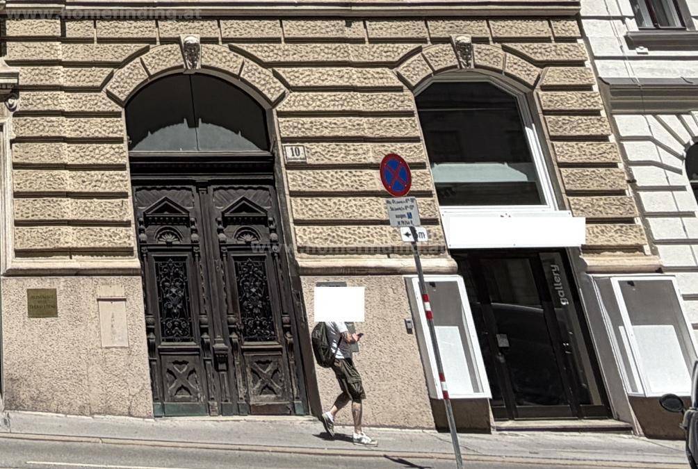 Historische Fassade mit verzierter Holztür und moderner Glasfront im Stadtzentrum.