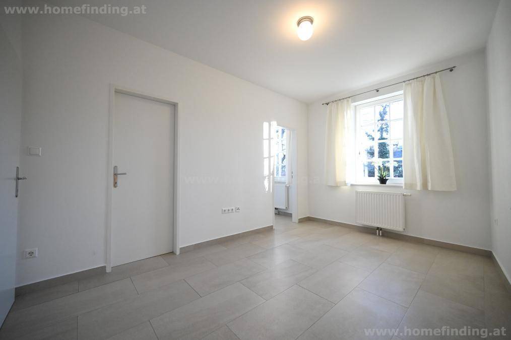 Helles Schlafzimmer mit Fliesenboden und Fenster mit Vorhängen, ideal für individuelle Einrichtung.