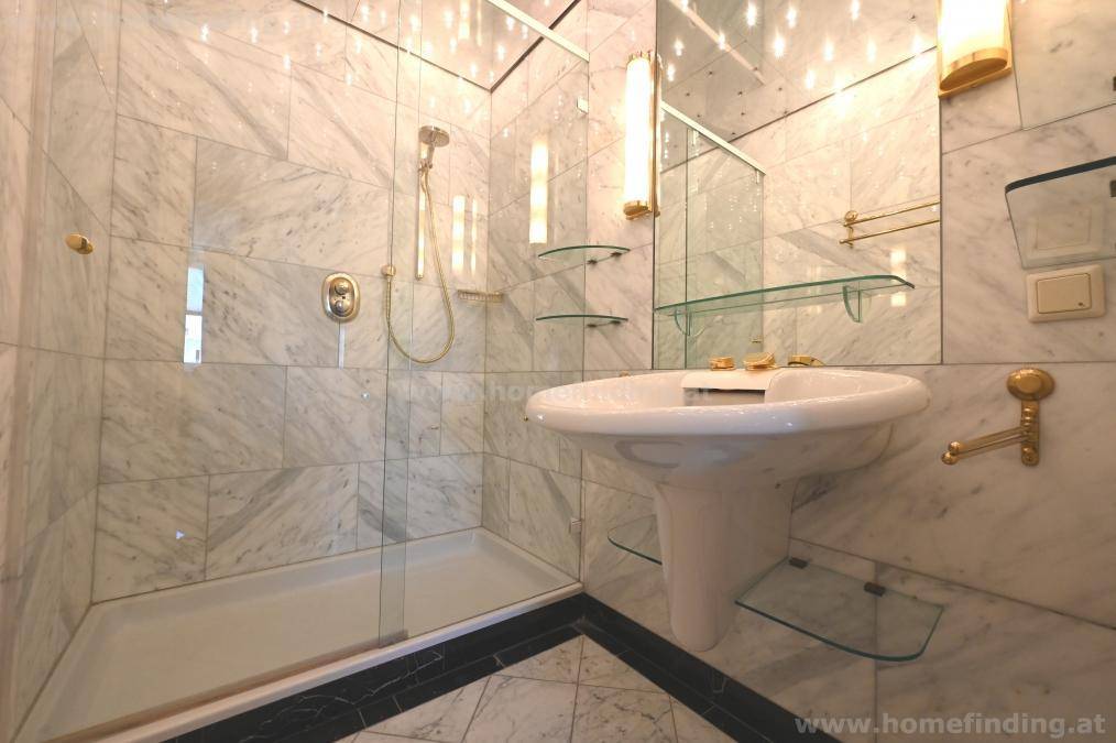 Modernes Badezimmer mit Marmorfliesen, begehbarer Dusche und goldenen Armaturen.