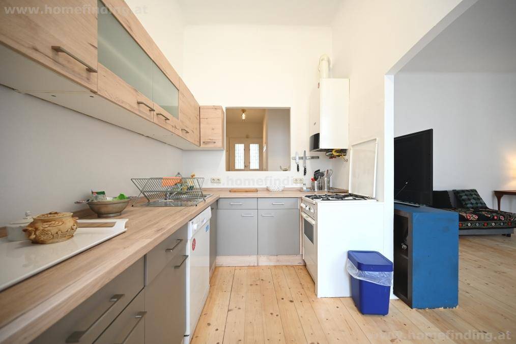 Funktionale Küche mit Gasherd und Boiler, die einen Blick in den angrenzenden Wohnbereich bietet.