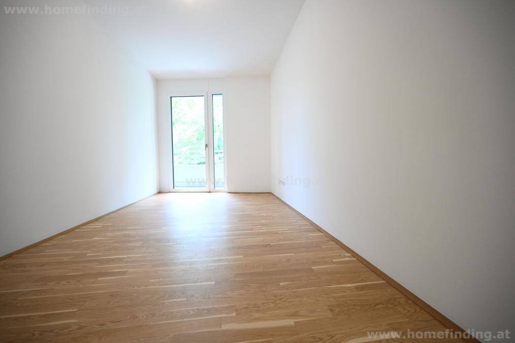 Helles Zimmer mit Holzboden und bodentiefen Fenstern, die viel Licht spenden.