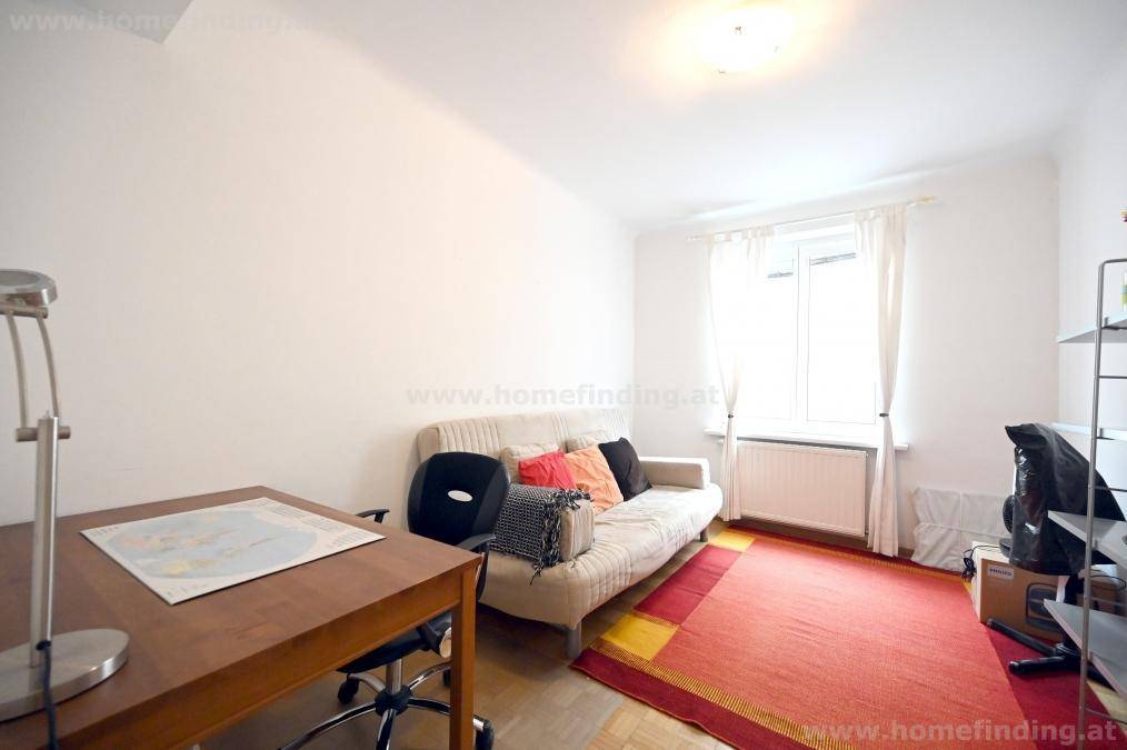 Funktionales Arbeitszimmer mit Schreibtisch, Sofa und einem Fenster, ideal für Home-Office oder Gäste.