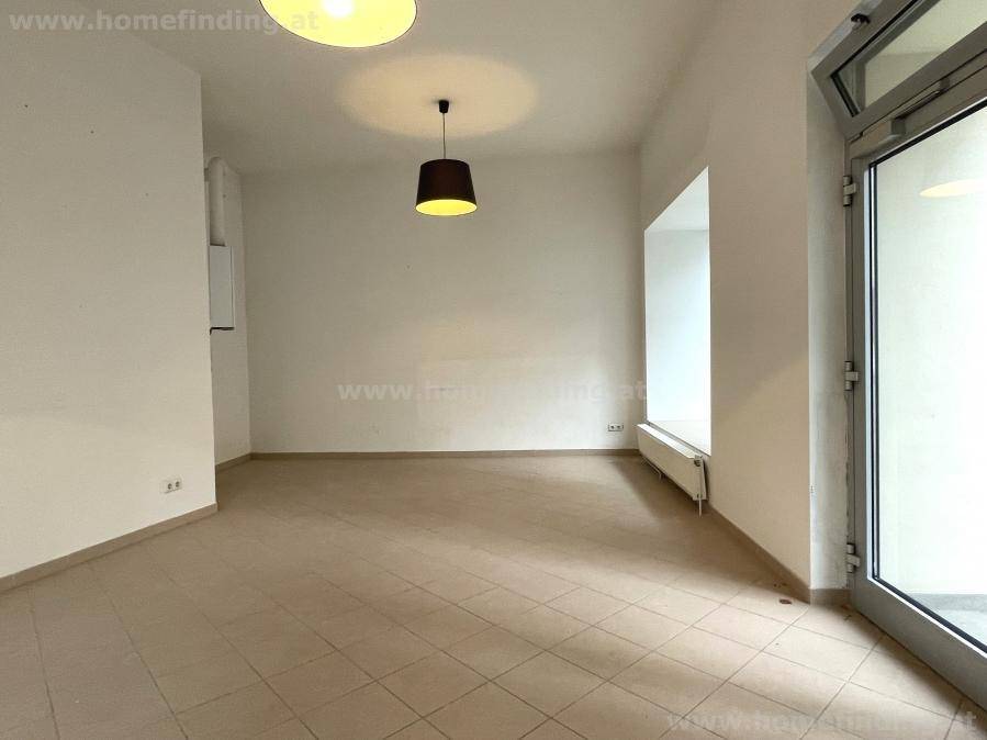 Geräumiger, leerer Raum mit Fliesenboden und viel Tageslicht durch die Fensterfront.